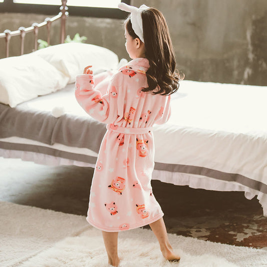 Child wearing a pink robe with cartoon characters in a bedroom setting