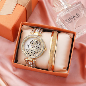 Luxury watch and bracelet set in an orange box with a perfume bottle in the background.