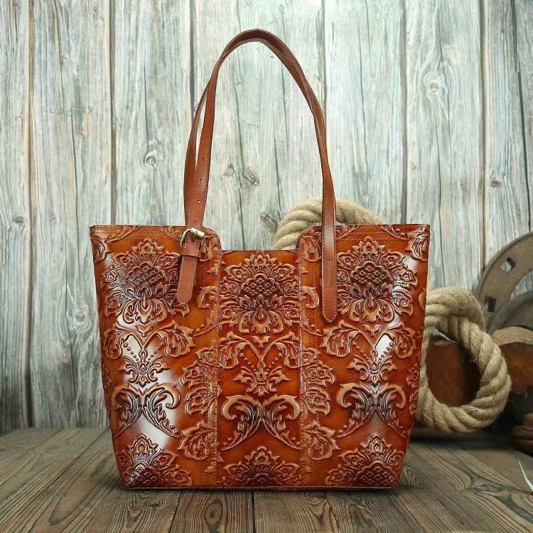 Brown leather tote bag with intricate patterns on a wooden surface.