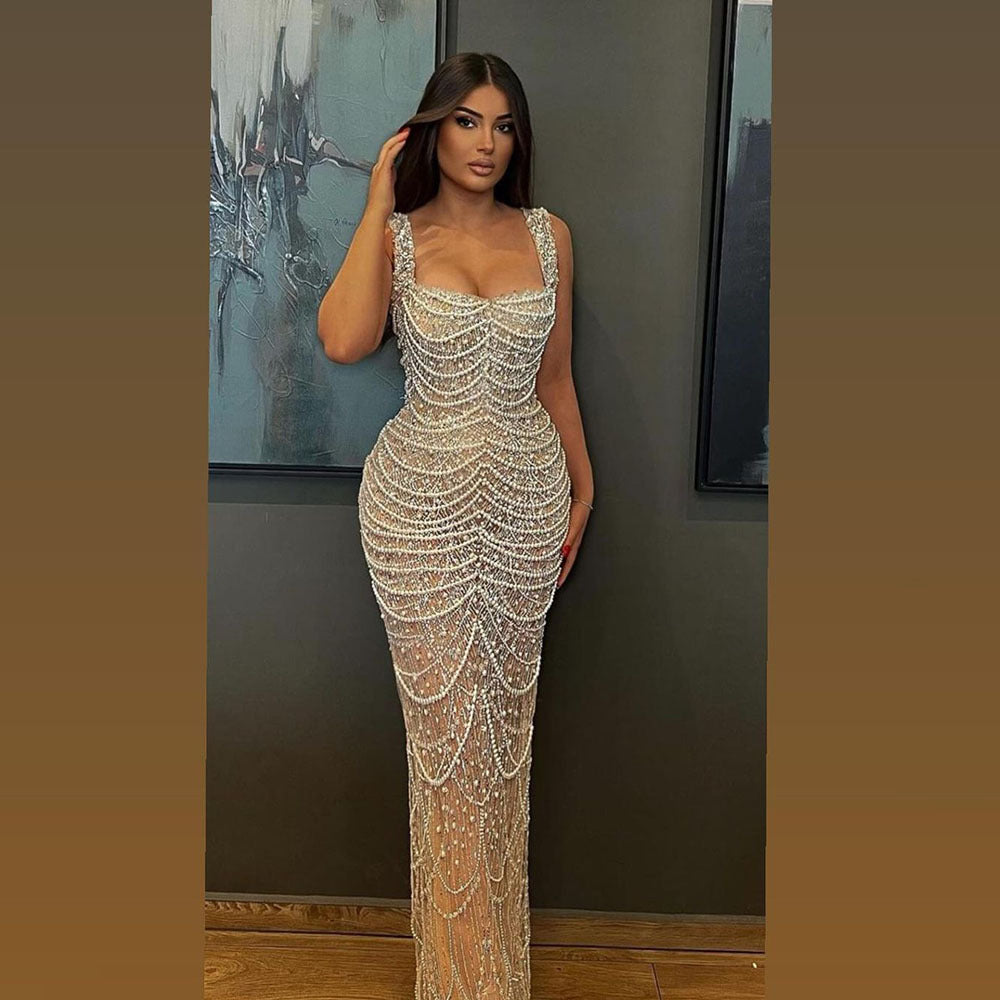 Woman in a sparkling evening gown standing against a wall with framed artwork.