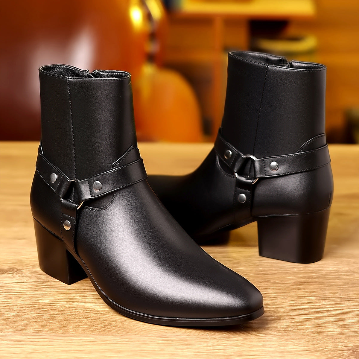 Pair of black leather boots with buckles on a wooden surface