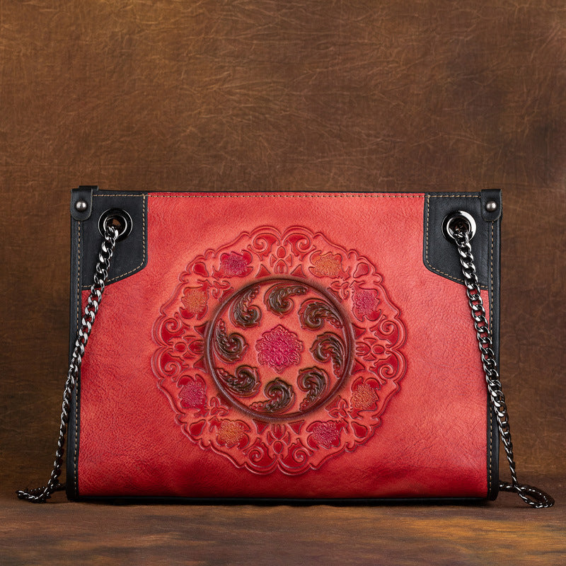 Red leather handbag with intricate design on a brown background