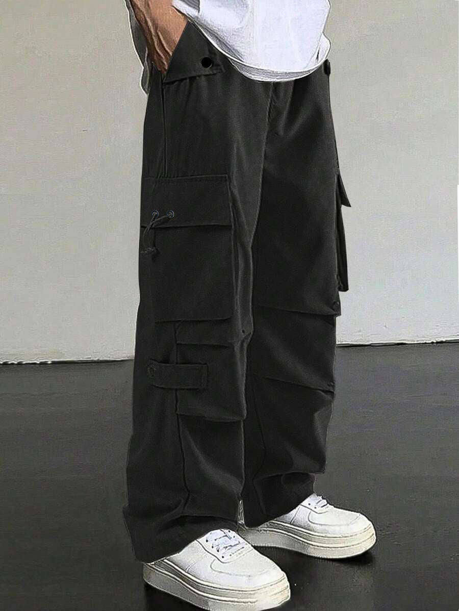 Person wearing black cargo pants and white sneakers on a plain background