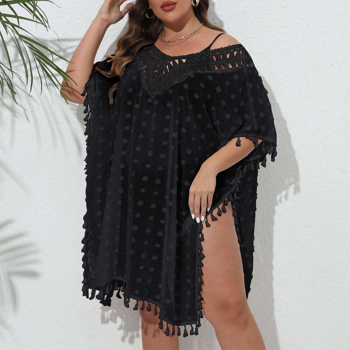 Woman wearing a black off-shoulder dress with tassels against a white background