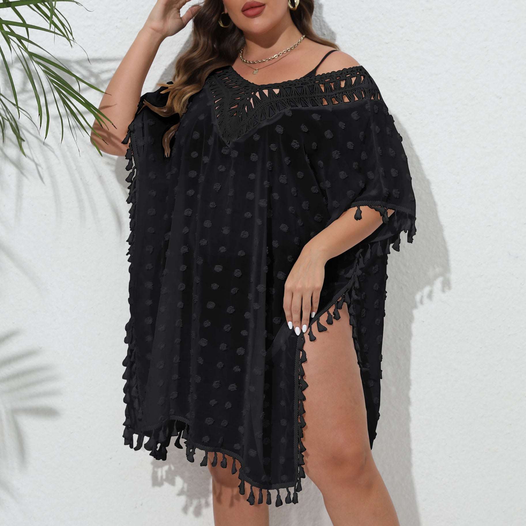 Woman wearing a black off-shoulder dress with tassels against a white background