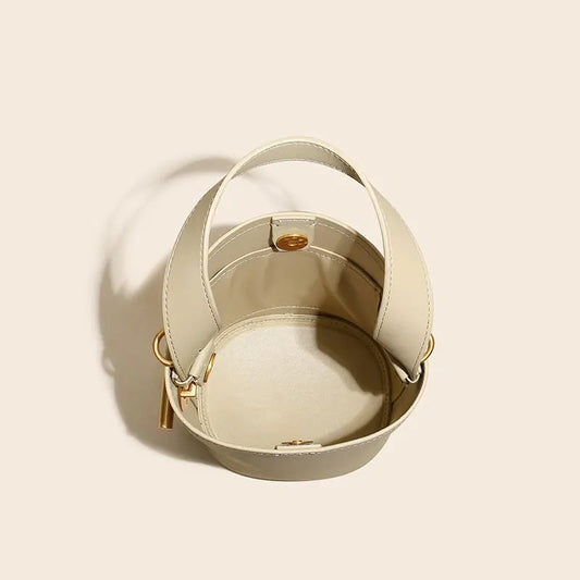 Beige handbag with gold accents on a light beige background