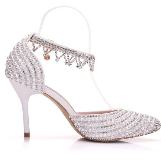 White high-heeled shoe with pearl and crystal embellishments on a white background
