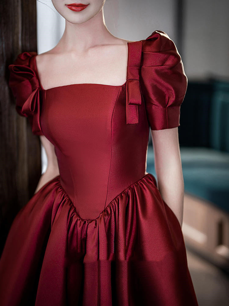 Red dress with puff sleeves and a bow detail on a blurred background