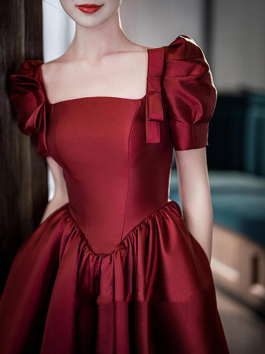Red dress with puff sleeves and a bow detail on a blurred background