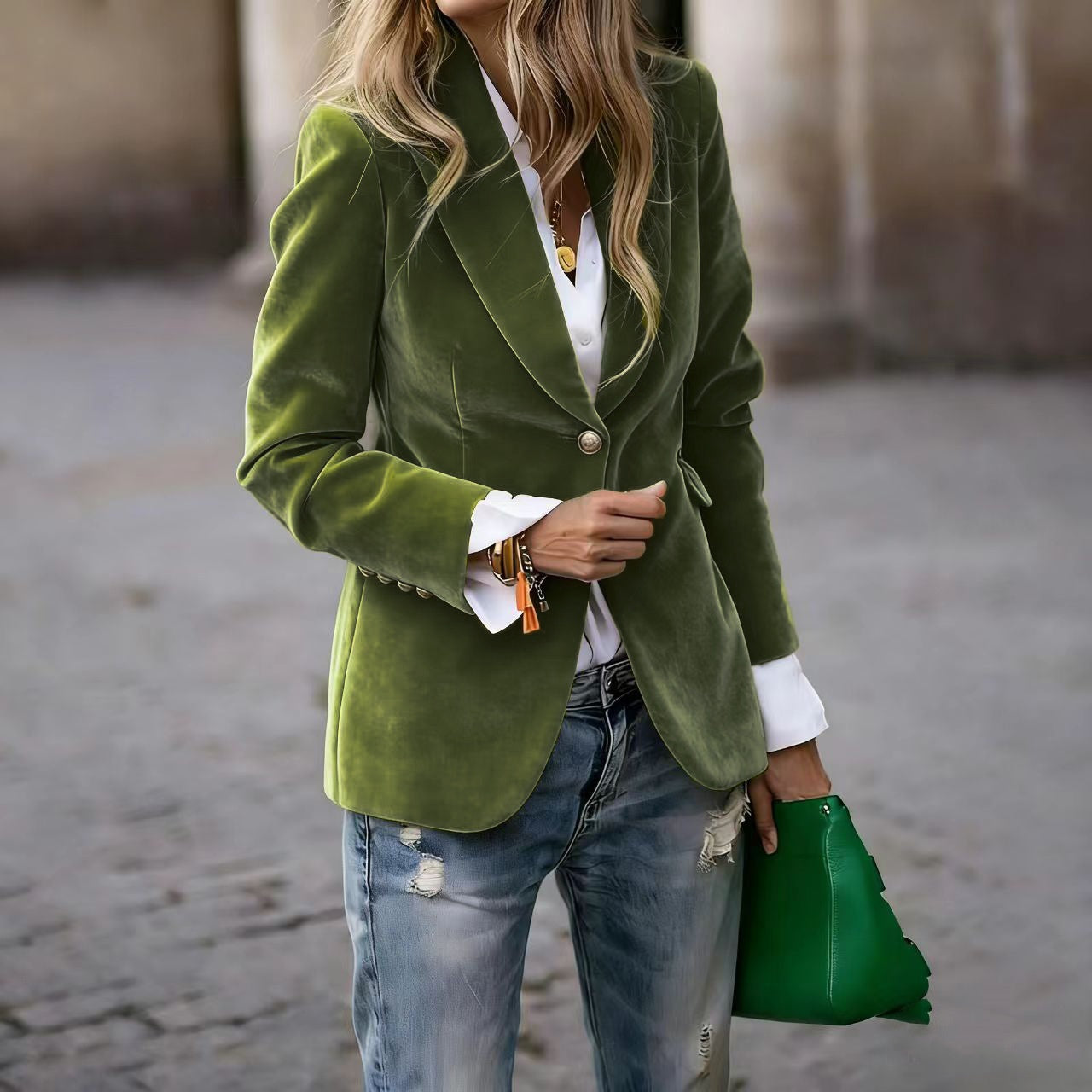 Person wearing a green blazer and holding a green clutch.