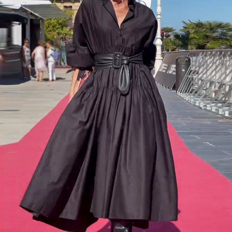 Person wearing a black dress on a red carpet with a blurred background