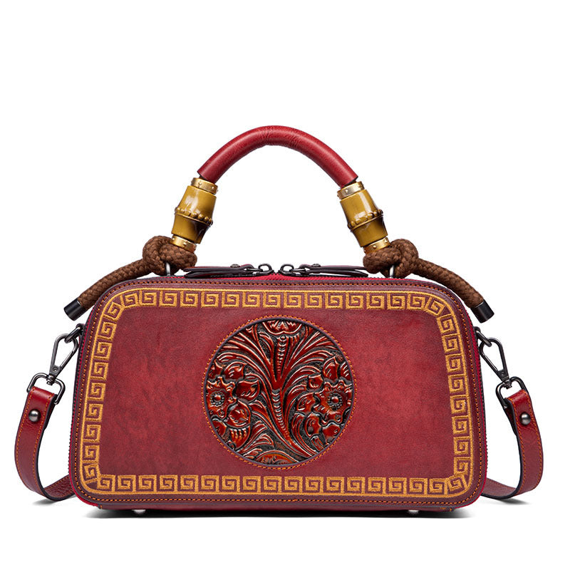 Red handbag with intricate designs and a decorative handle on a white background