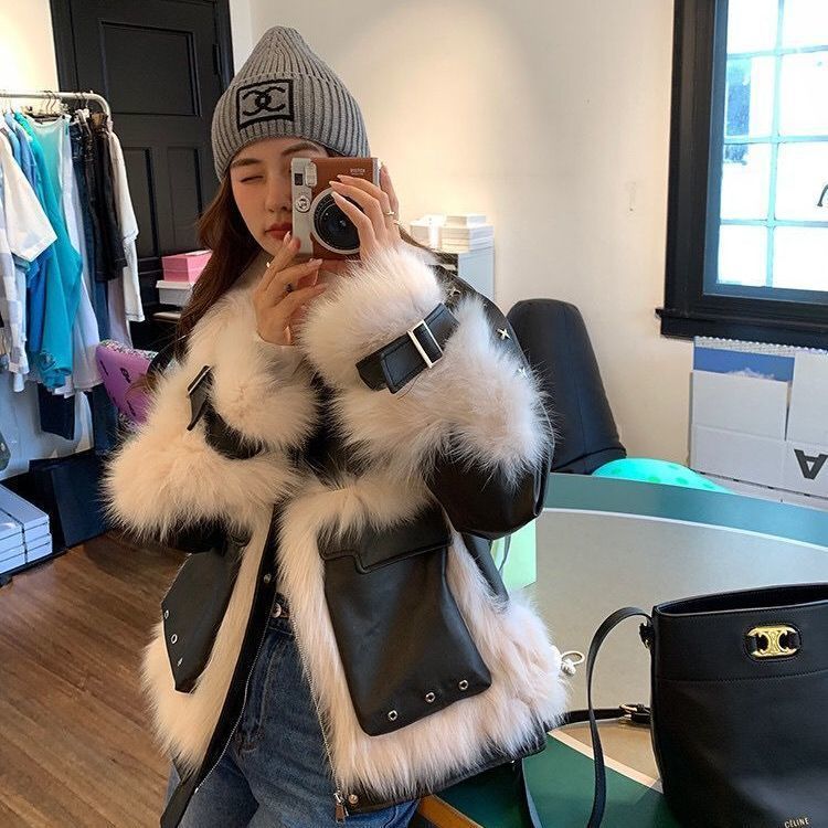 Person wearing a fur-trimmed coat with a black bag in a store setting