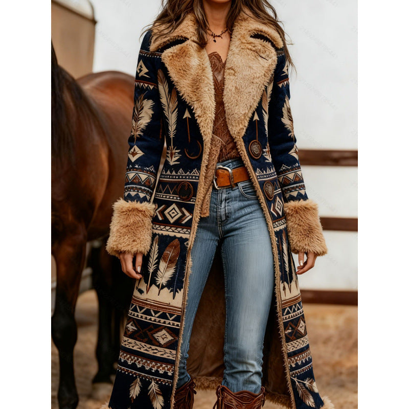 A woman wearing a long navy blue patterned coat with beige faux fur trim, blue jeans, and brown boots, standing in front of a horse in a rustic barn setting.