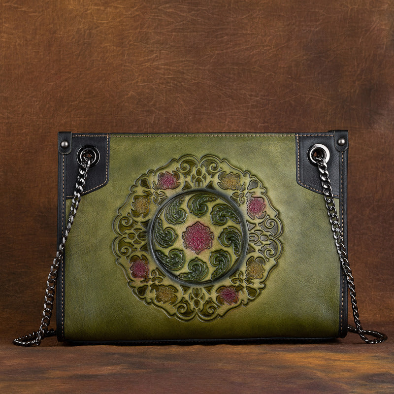 Green leather handbag with intricate design on a brown background