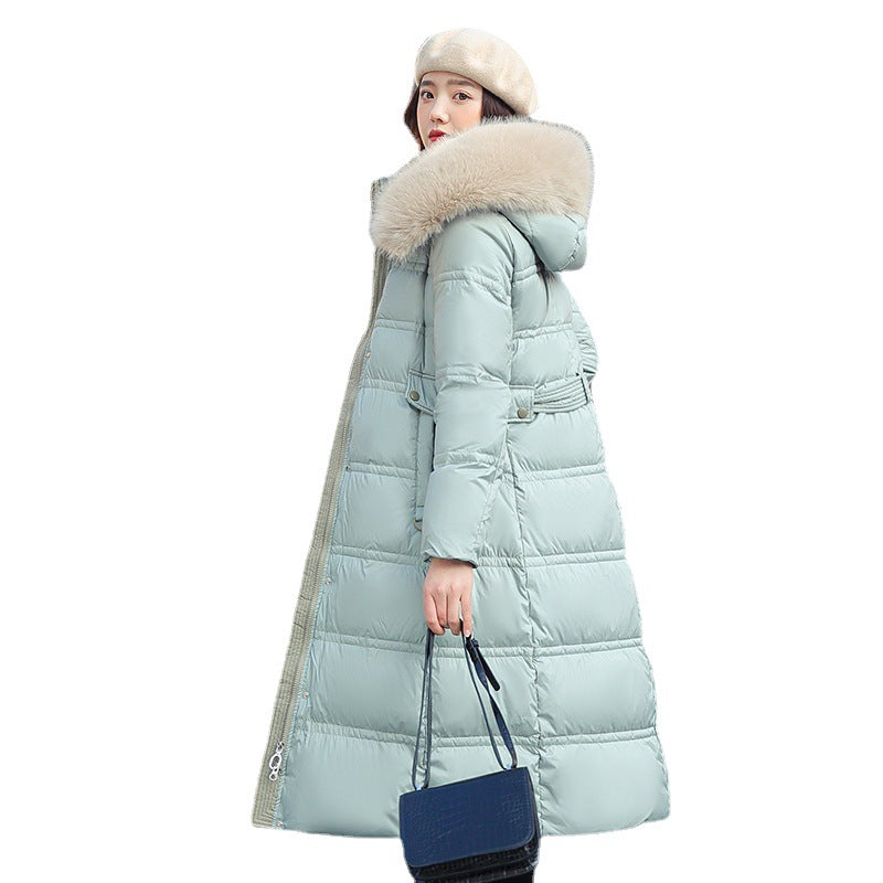 Woman wearing a long light blue puffer coat with a fur-lined hood on a white background