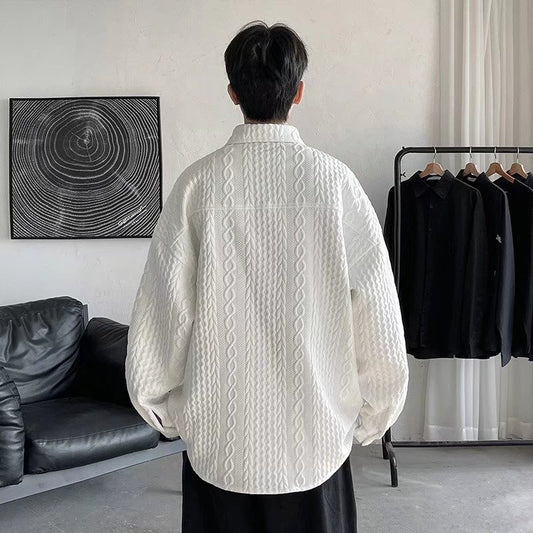 Person wearing a white cable knit sweater in a room with a black leather sofa and clothing rack.