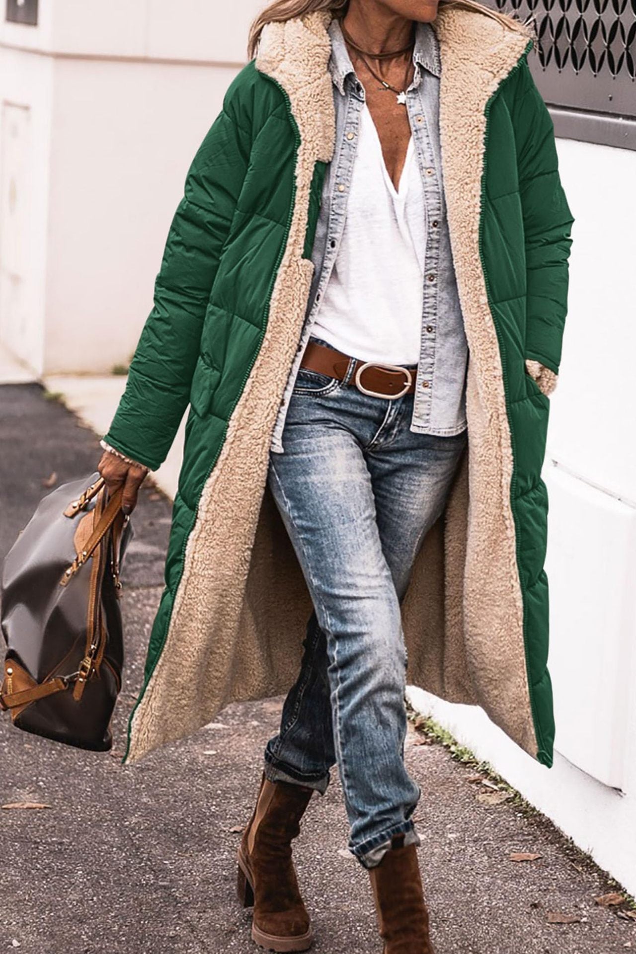 Person wearing a long green coat with a beige sherpa lining, blue jeans, and brown boots.