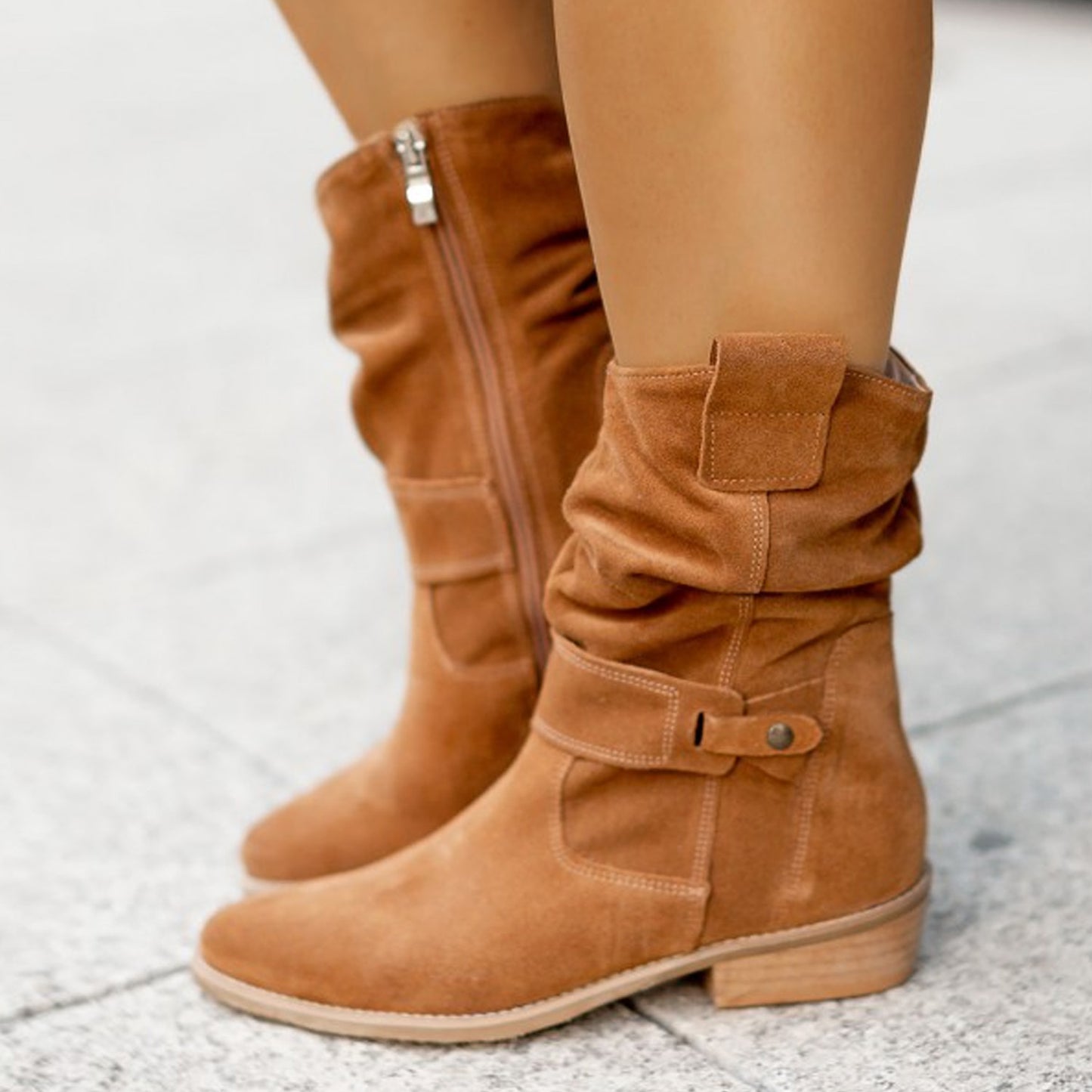 Tan knee-high boots worn by a person on a light gray background