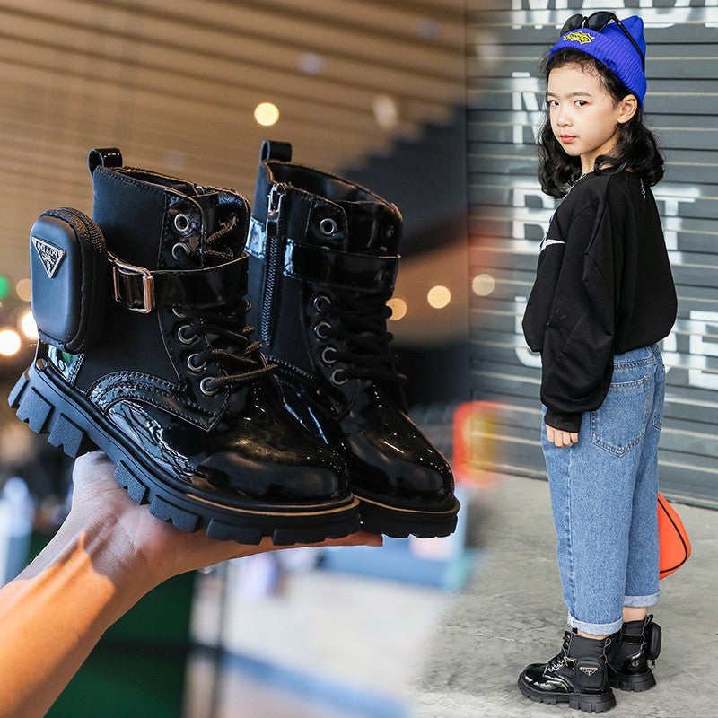 Black boots with a zipper held up, with a child wearing similar boots in the background.