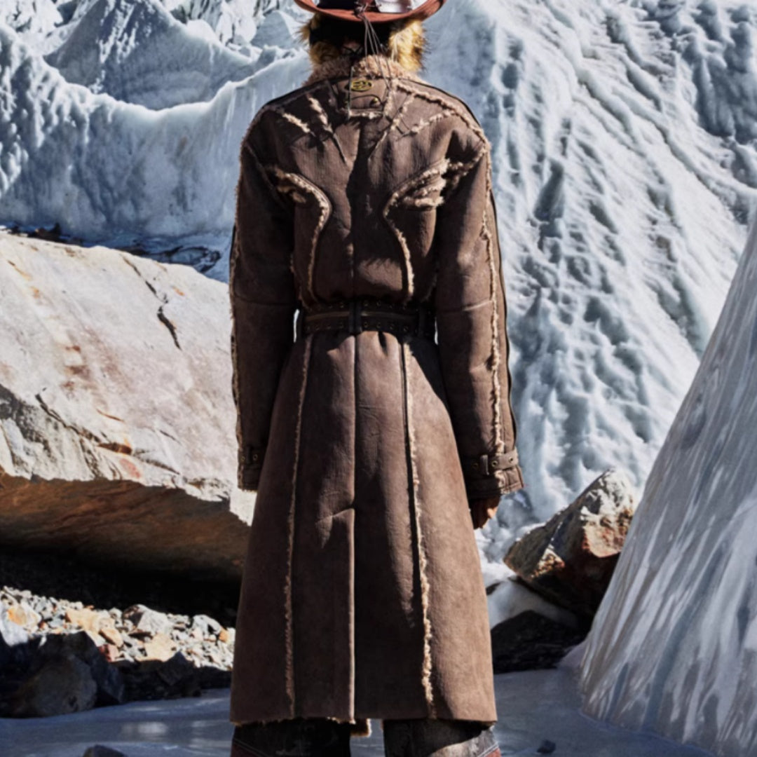 Person wearing a long brown coat standing in a snowy landscape