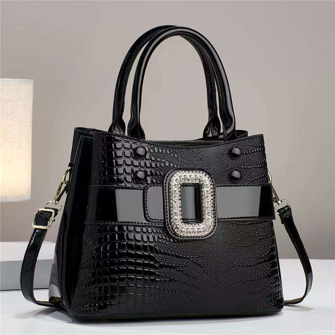 Black handbag with a decorative buckle on a neutral background