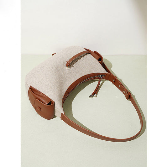 Beige handbag with brown leather accents on a light beige background