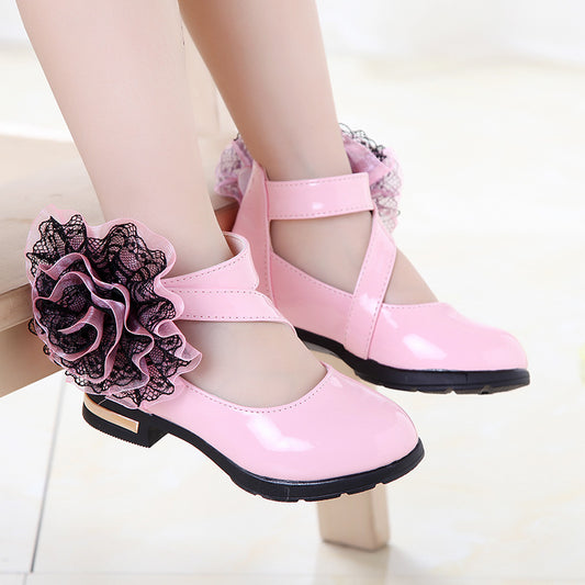 Pink shoes with black ruffles worn by a person on a light background