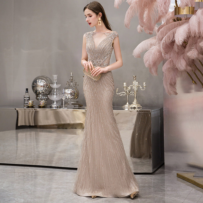 Woman in a beaded evening gown standing in an elegant room with decorative elements.