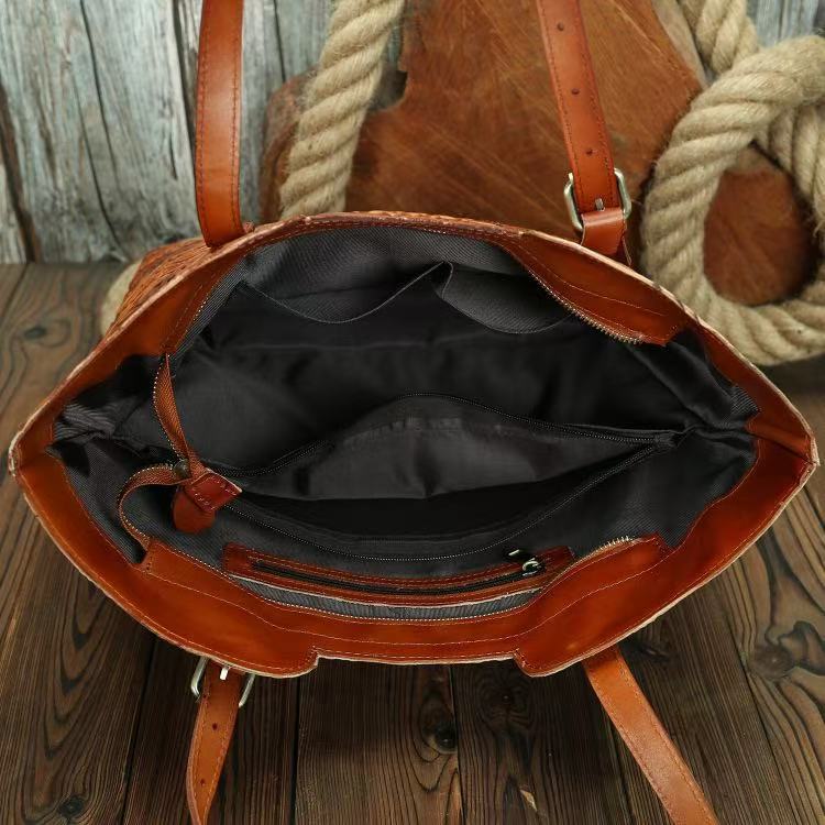 Brown leather bag with black interior on a wooden surface