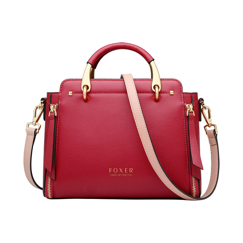 Red handbag with gold accents and a pink strap on a white background