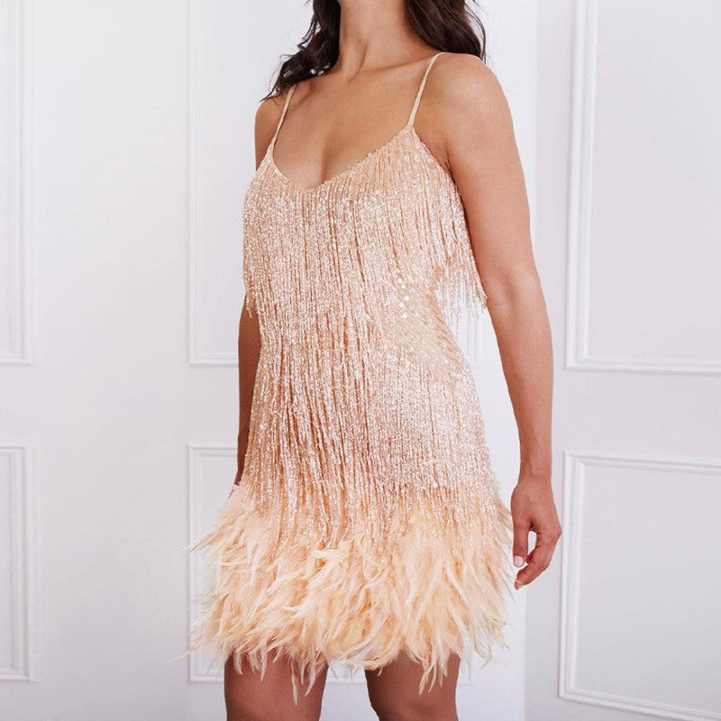 Woman wearing a beige fringe dress against a white paneled wall.