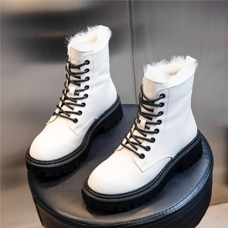 White winter boots with black laces on a dark surface