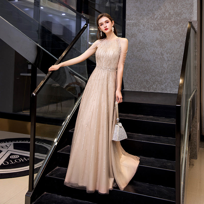 Woman in a beige evening gown standing on a staircase