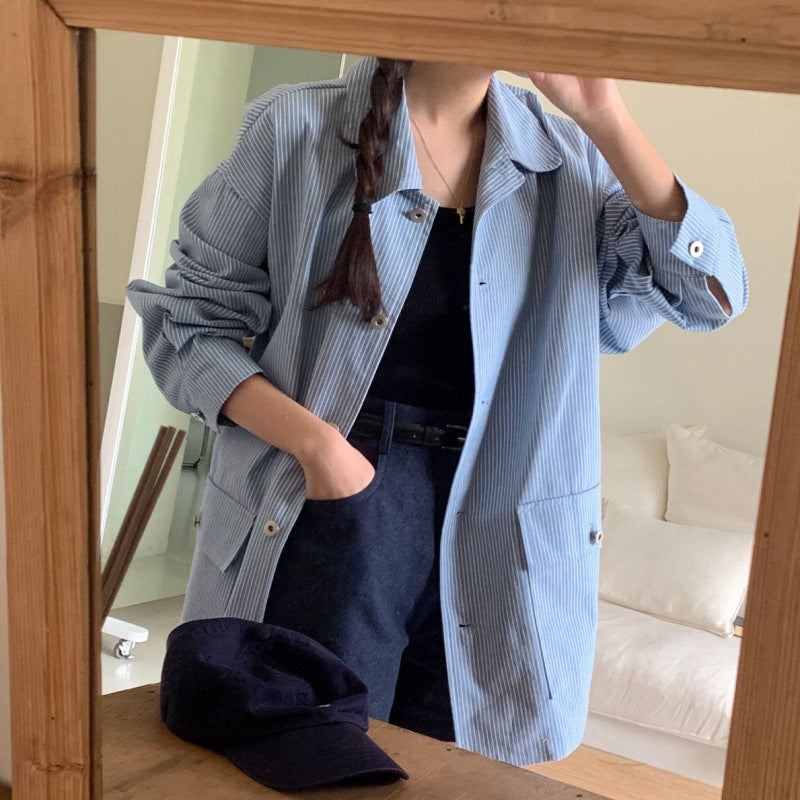 Person wearing a light blue striped shirt in front of a mirror.