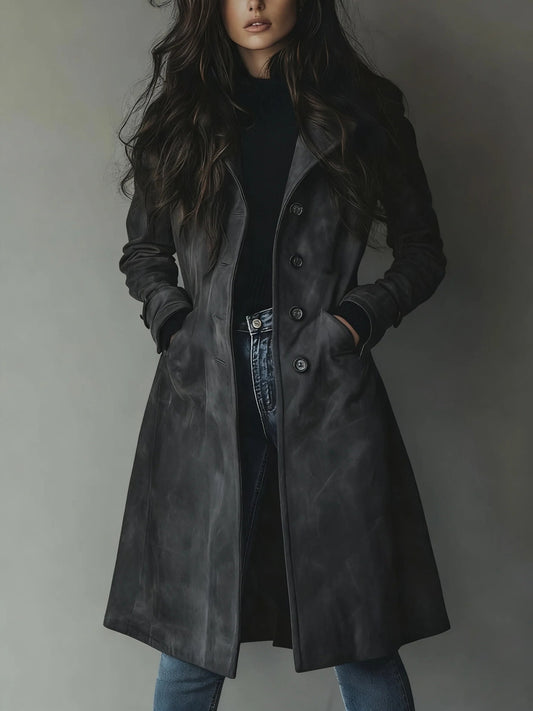 Woman wearing a long dark coat against a plain background