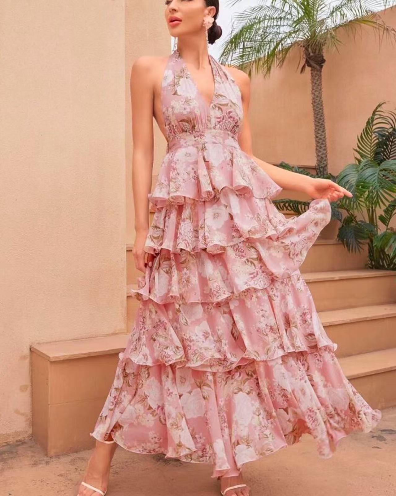 Woman wearing a pink floral dress standing outdoors with a palm tree in the background