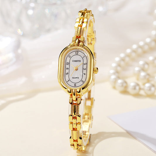 Gold wristwatch with a white face on a soft, blurred background
