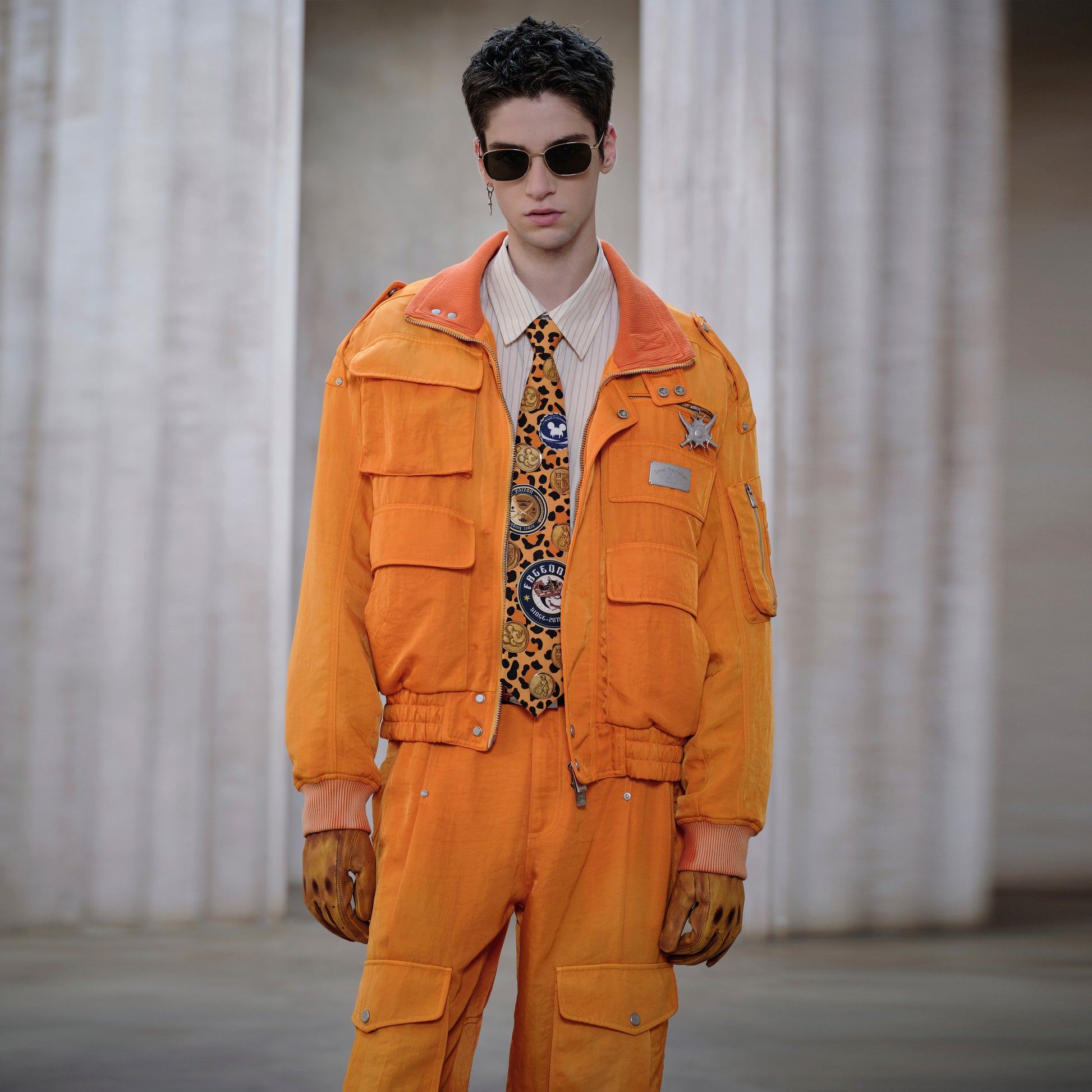 Person wearing an orange outfit with a patterned tie in a neutral setting