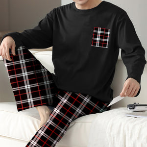 Person wearing a black long-sleeve shirt with a plaid pocket and black plaid pants sitting on a white couch.