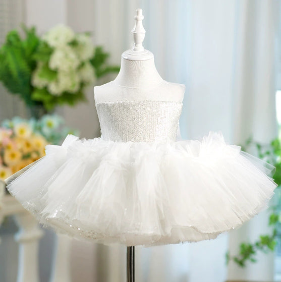 White dress with a fluffy skirt on a mannequin against a blurred floral background
