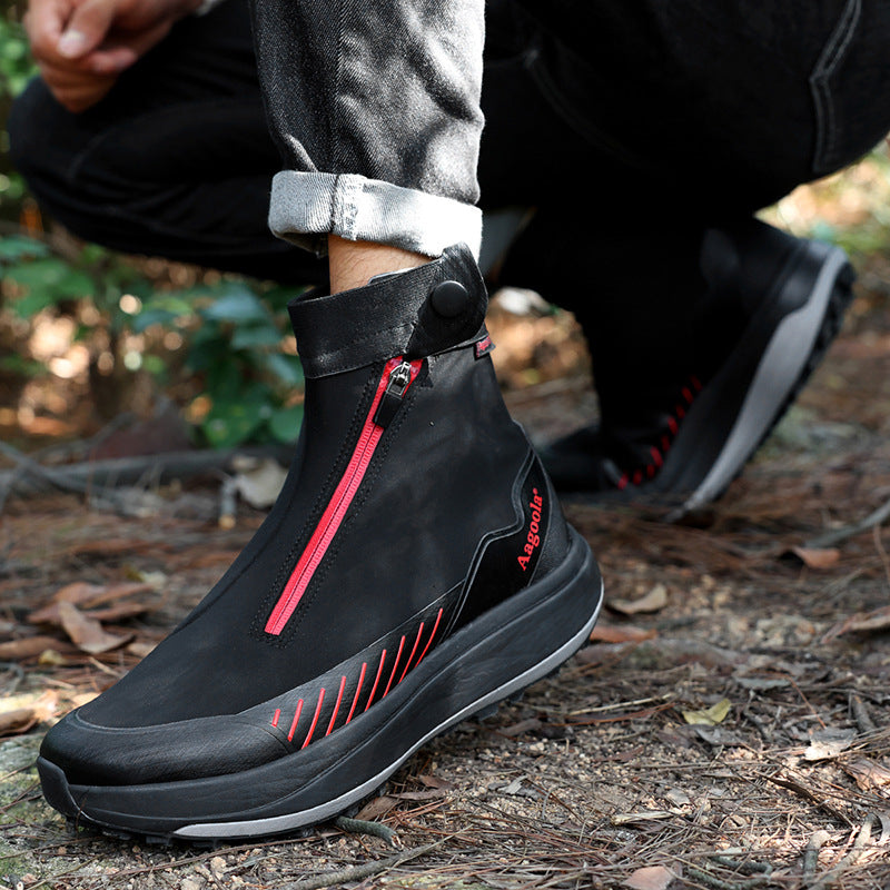 Black hiking boots with red zippers worn by a person in an outdoor setting.