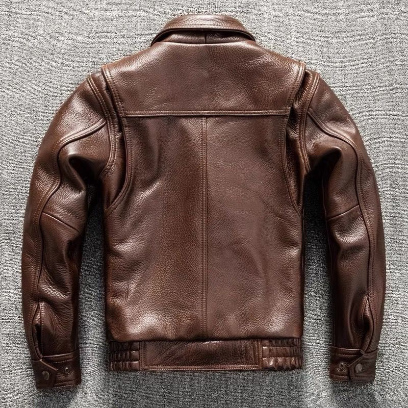 A brown leather jacket shown from the back, laid flat on a textured gray background.