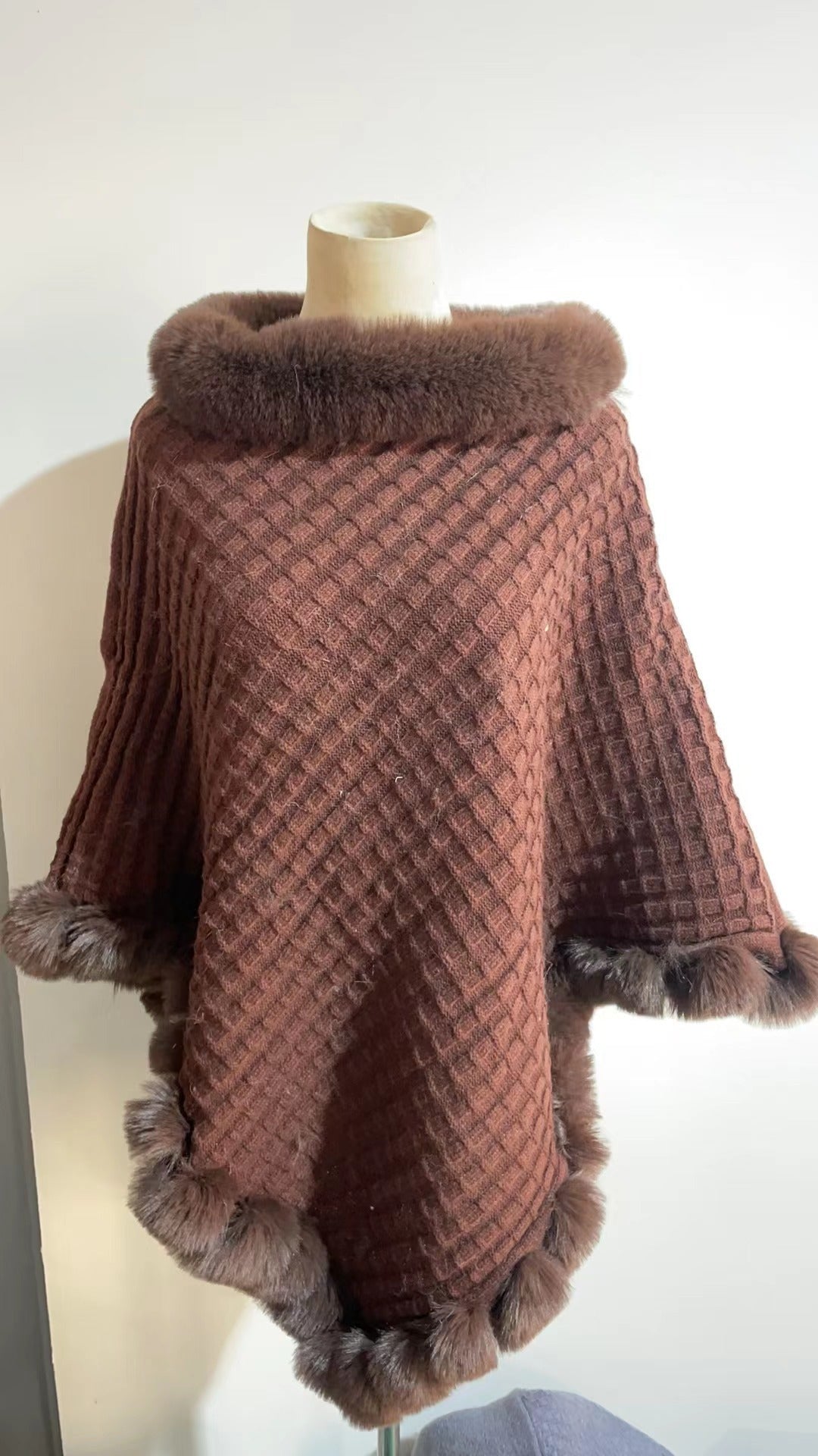 Brown textured poncho with fur trim on a mannequin against a white background