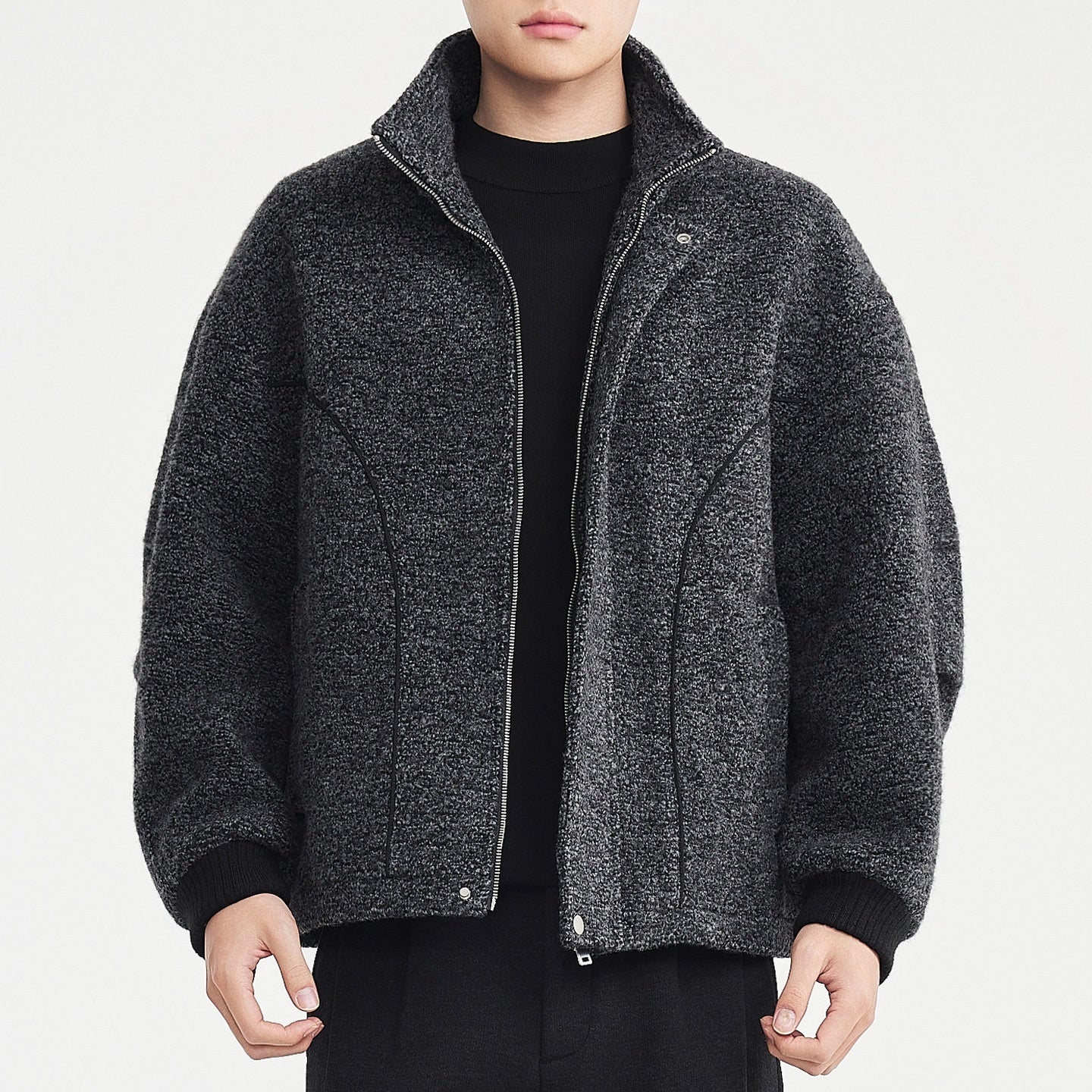 Person wearing a gray textured jacket on a light gray background