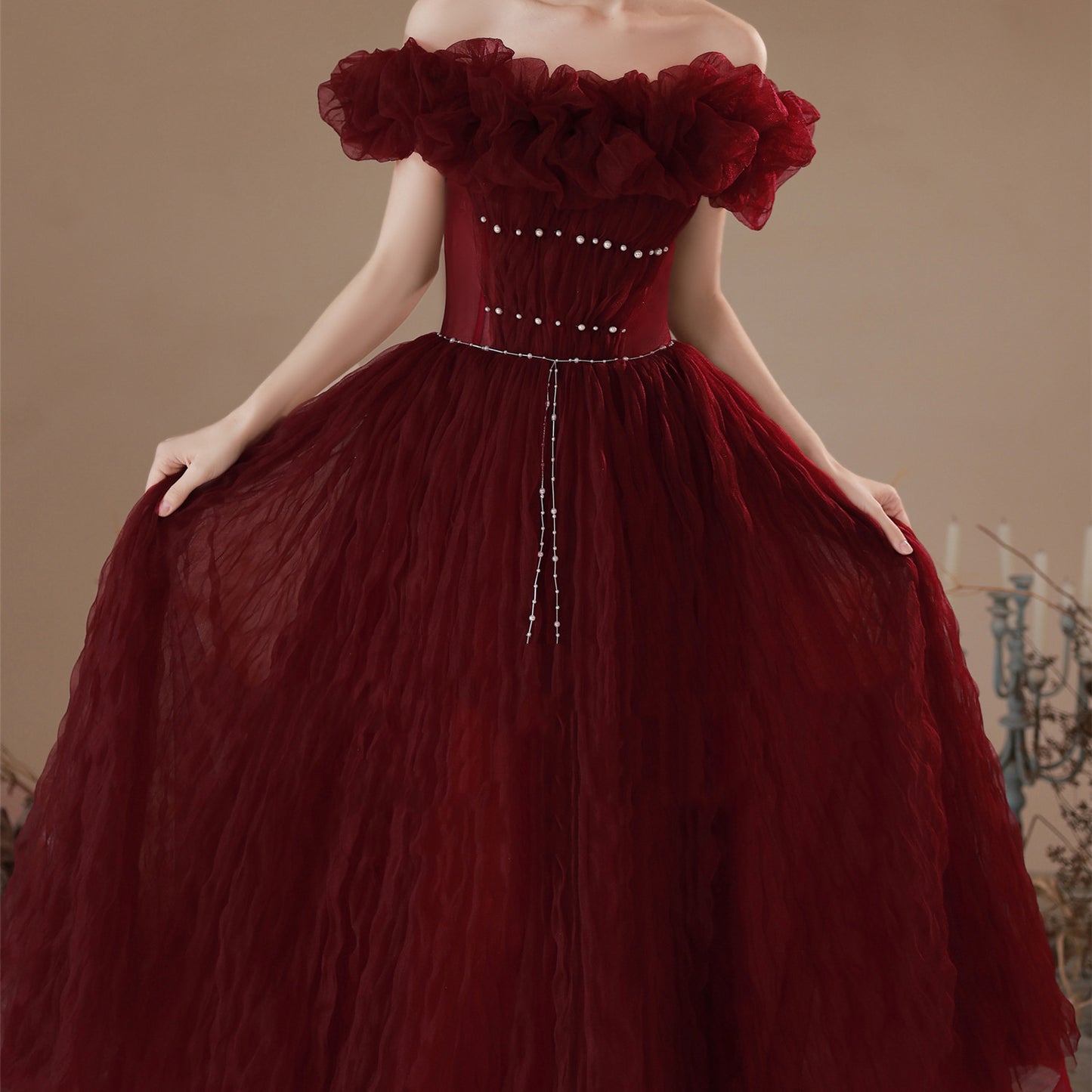 Red off-shoulder gown with floral details on a neutral background