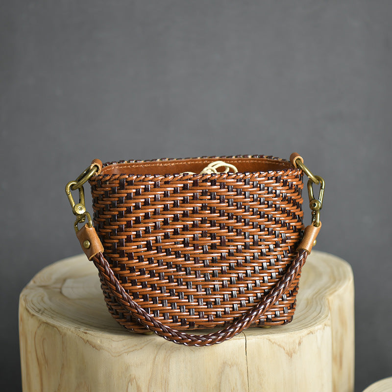 Woven handbag with brass hardware on a wooden block against a gray background