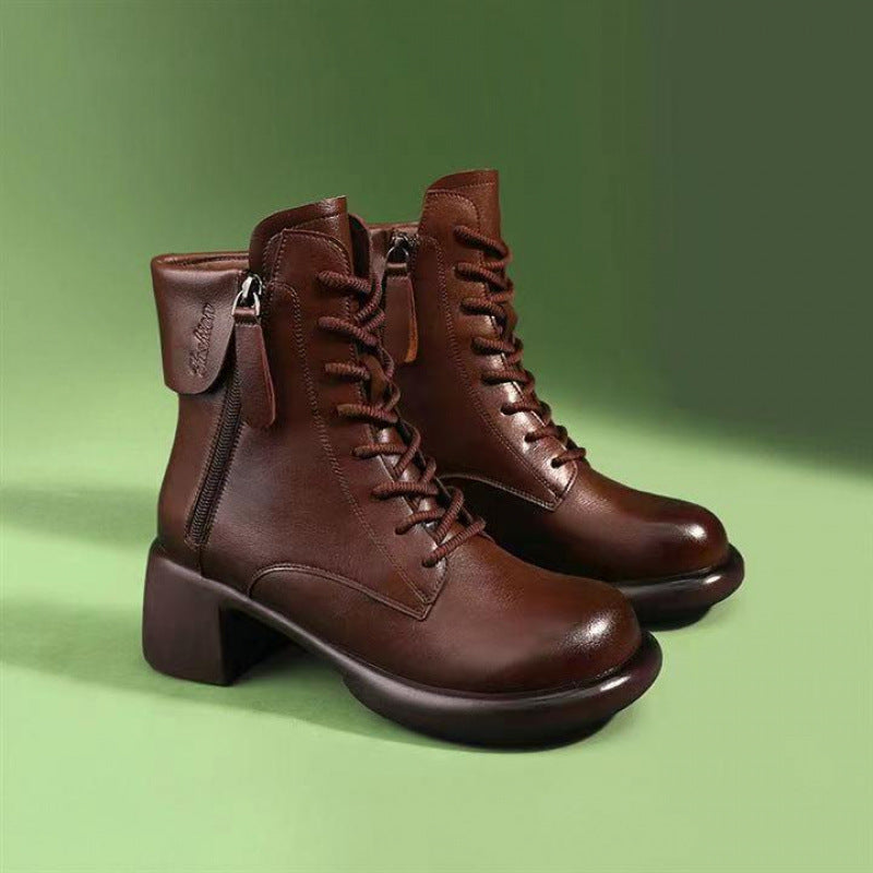 Pair of brown leather boots with a zipper on a green background
