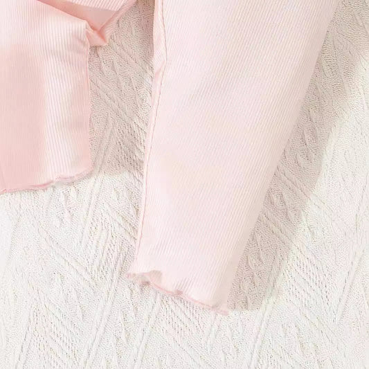 Close-up of pink ribbed fabric on a textured white surface