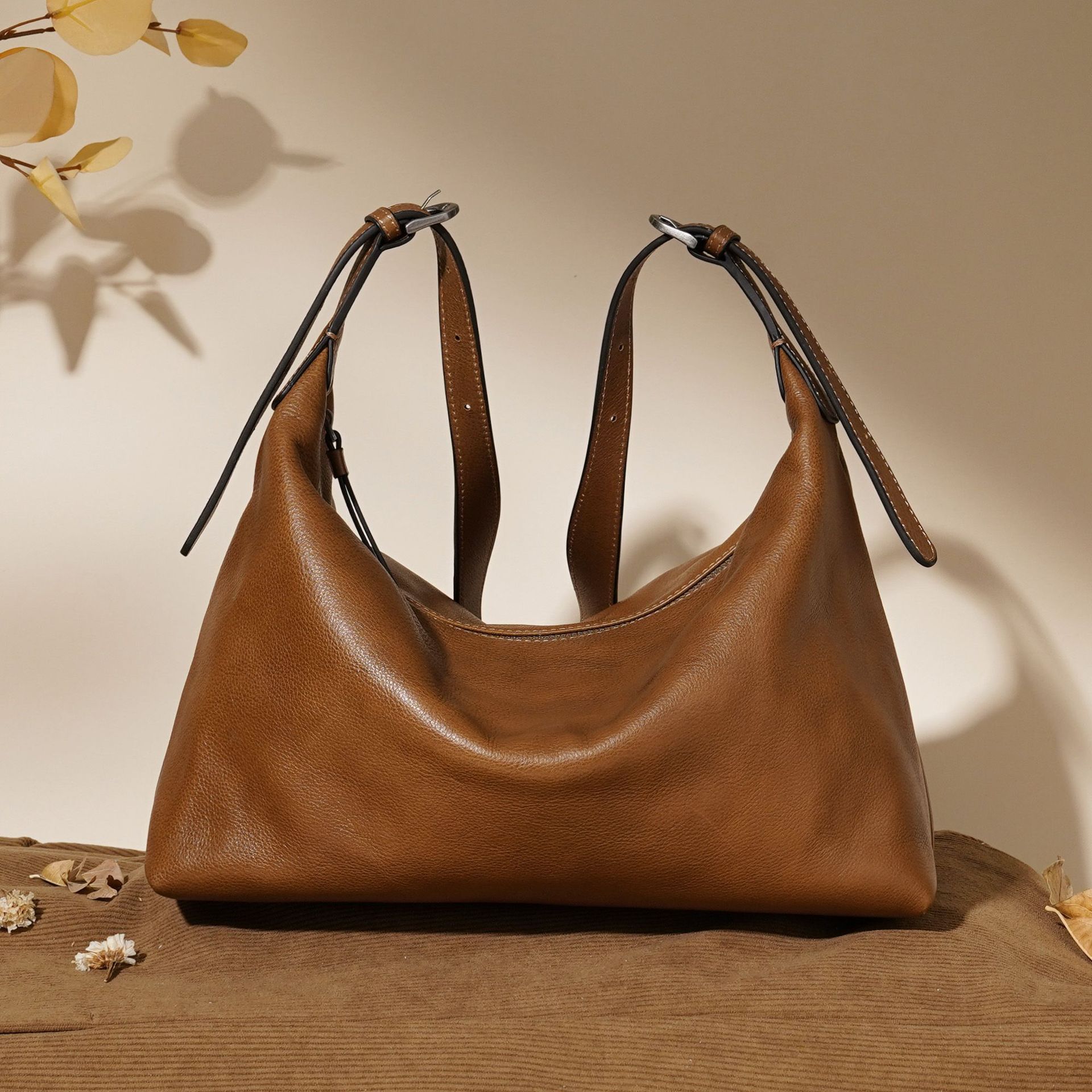 Brown leather handbag on a textured surface with a neutral background